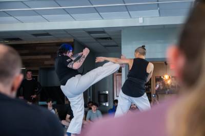 karate demo with two combatants fighting, on person is blocking a potential head kick